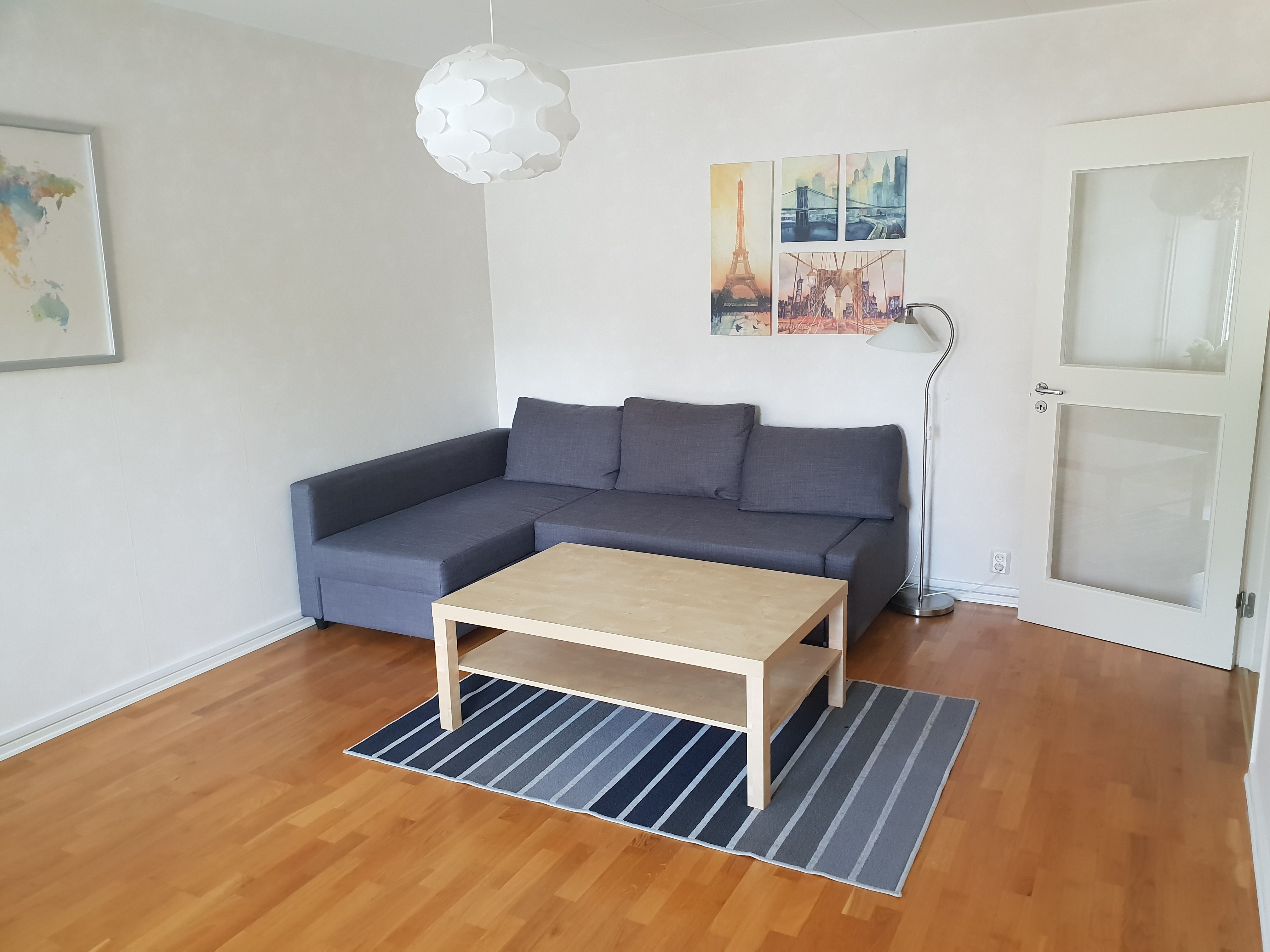 Bild på vardagsrum med soffa, soffbord och tavla på väggen