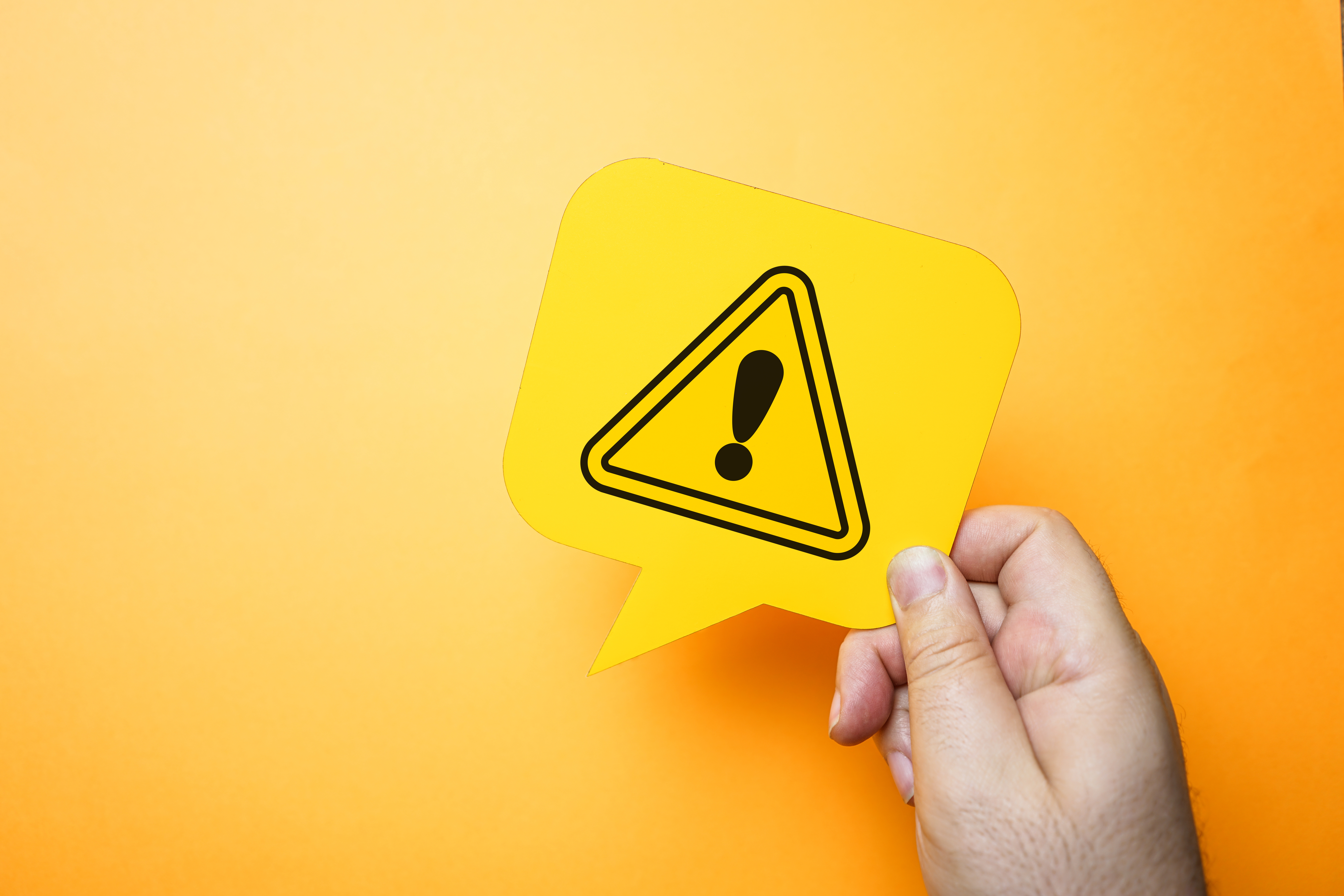 Hand som håller i en varningstriangel