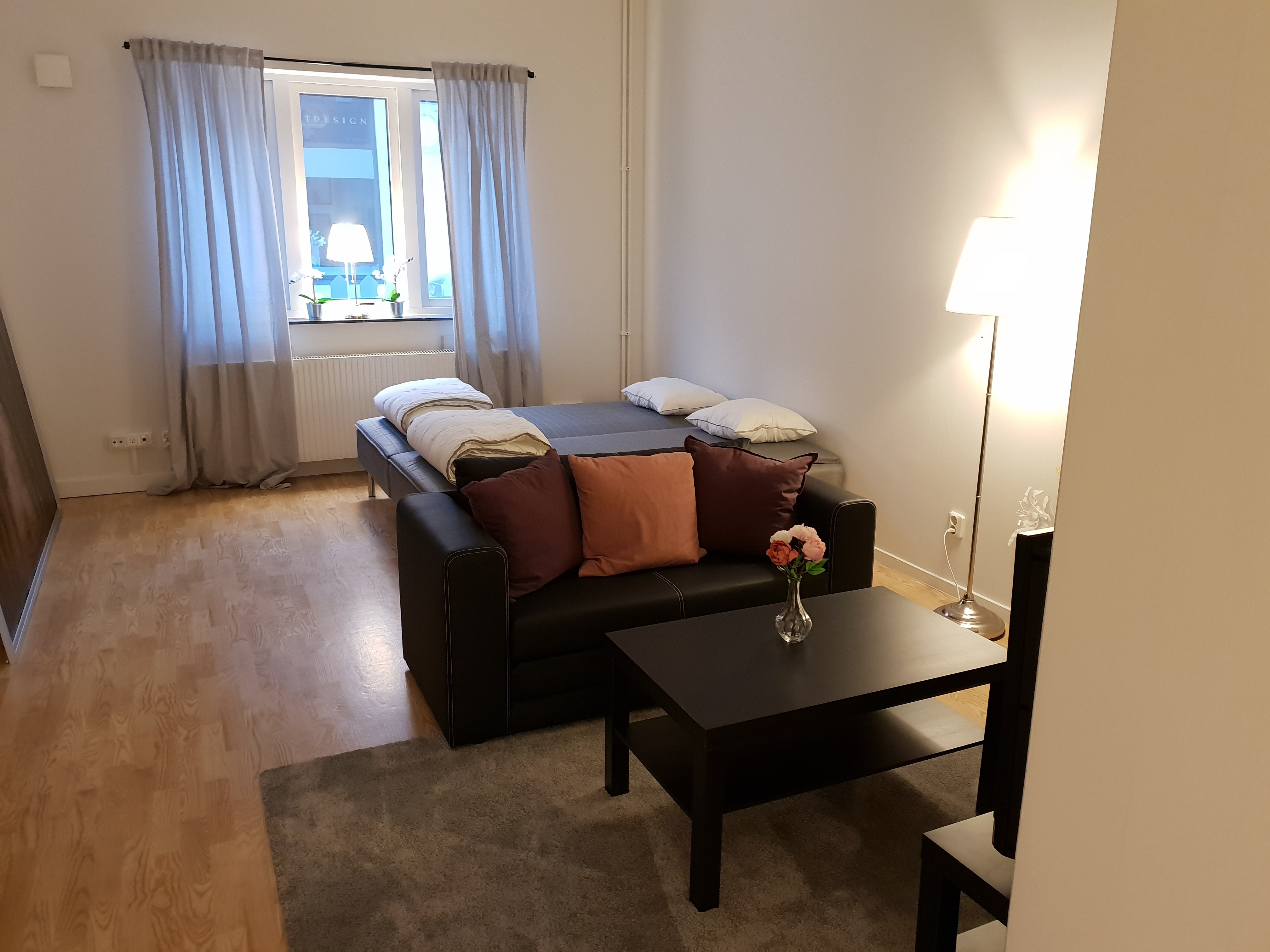 Vardagsrum med soffa, soffbord och två enkelsängar i bakgrunden