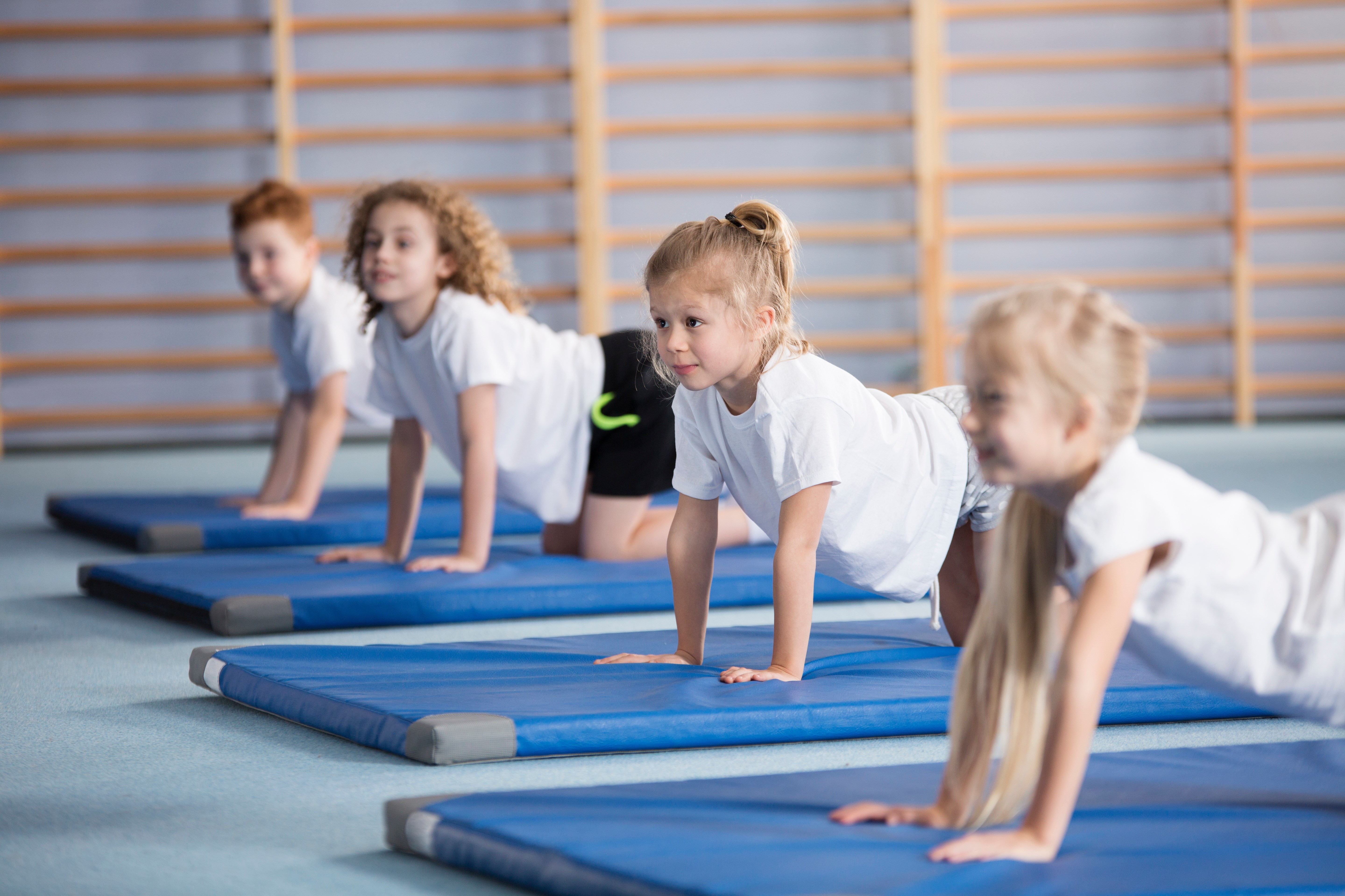 Fyra barn står på alla fyra på gymnastikmattor