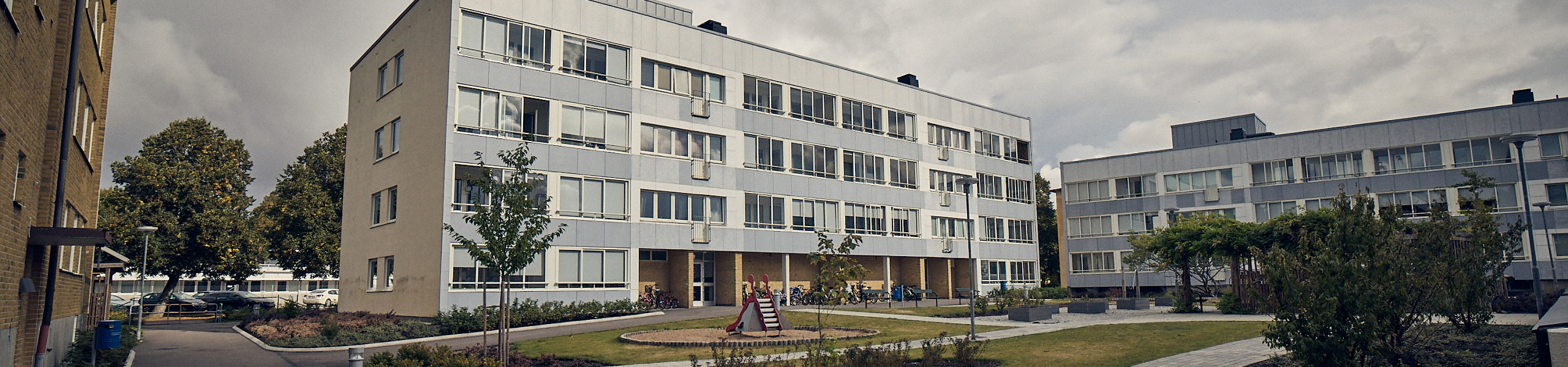Flerfamiljshus i gult tegel med balkonger och ljusgrå fasadskivor
